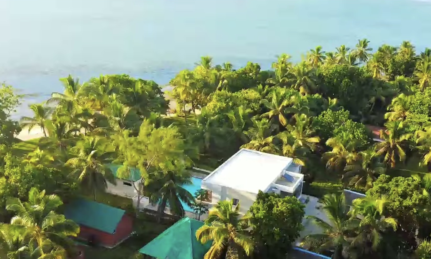 Golden light over the villa, the palms and the white sand beach