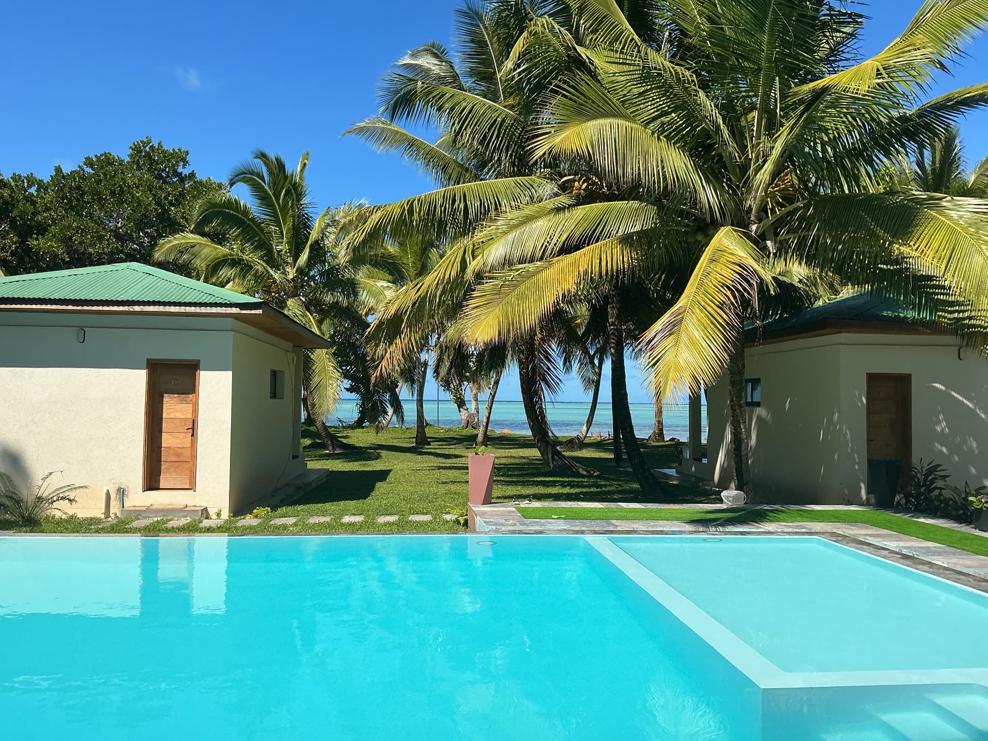 Two private bungalows with a pool and palm trees overlooking the ocean