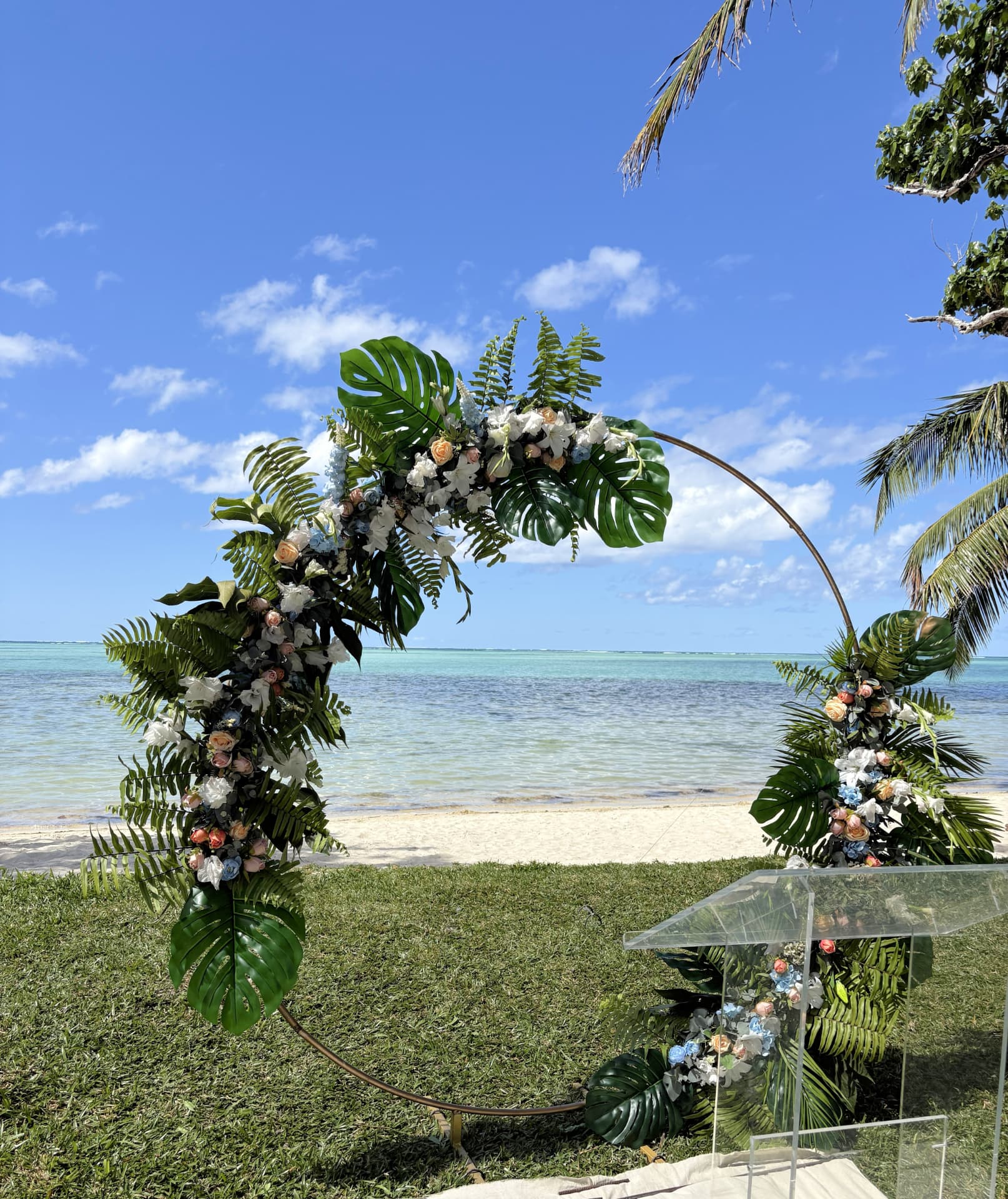 Circular floral wedding arch on the lawn overlooking the turquoise lagoon