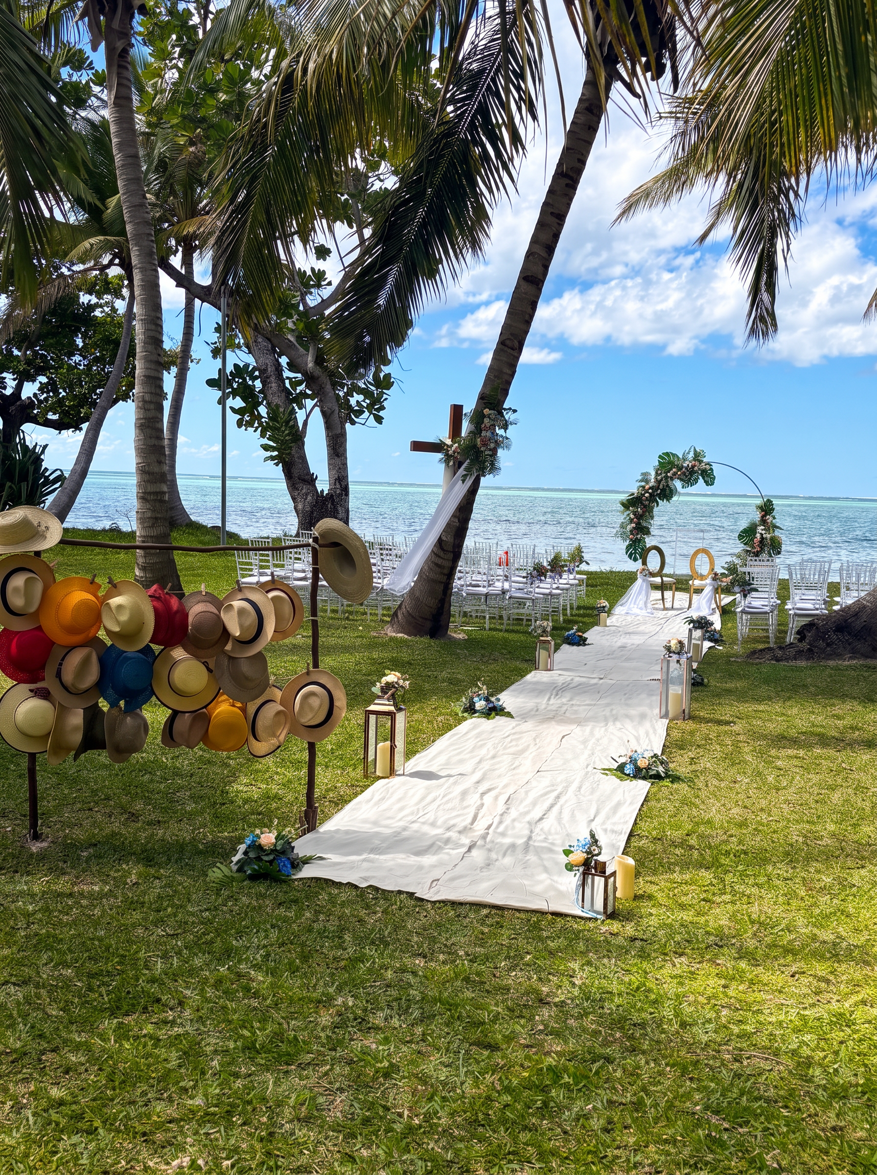 Beachside wedding ceremony with chairs, floral arch and aisle beneath coconut palms